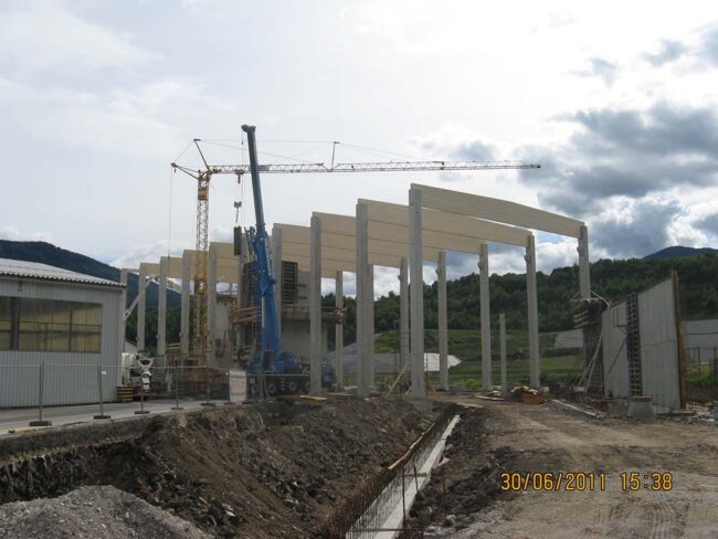 Betonbau und Bauarbeiten im Baufortschritt, Baustelle mit Kran, Holzrahmen und Baugerüsten, Entwicklung eines modernen Gebäudes im ländlichen Gebiet, Bauprojekt im Fortschritt, kreative Architektur im Entstehen.