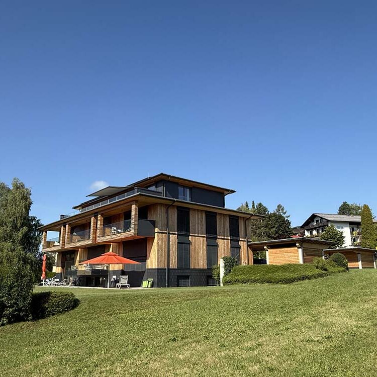 Moderne Holzarchitektur eines Ferienhauses in einer grünen Landschaft mit sonnigem Himmel.