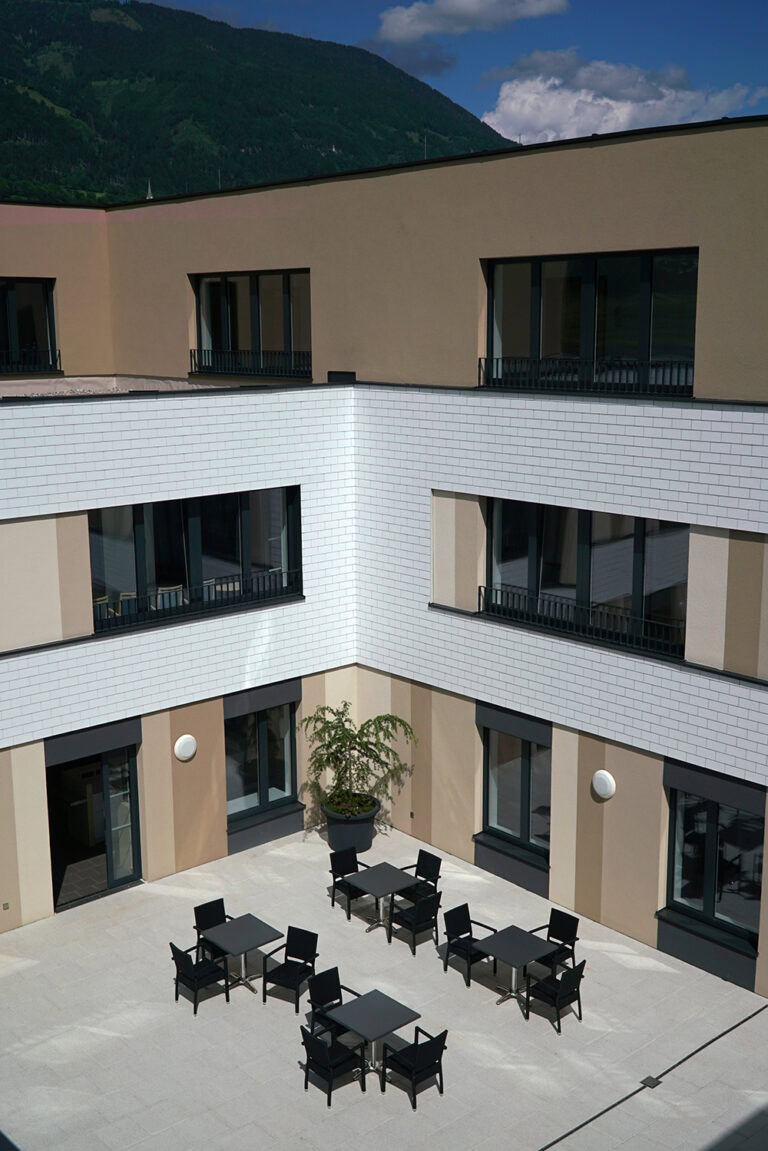 Moderne Hotelarchitektur mit Blick auf die Berge, helle Fassaden und großzügige Balkonflächen, ideal für einen angenehmen Aufenthalt in einer ruhigen Lage.