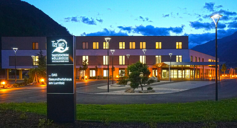 Modernes Gesundheitszentrum in den Alpen bei Nacht, blick auf das Tageszentrum Möllbrücke mit ansprechender Außenbeleuchtung und ruhiger Umgebung.