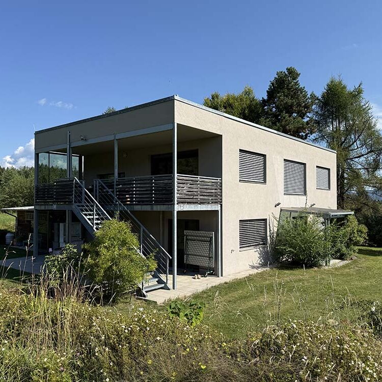 Moderne, zweistöckige Villa mit Terrasse im Grünen, umgeben von Bäumen und Wiesen, bei perfektem Wetter. Perfekt für nachhaltiges Bauen und zeitgenössisches Design.