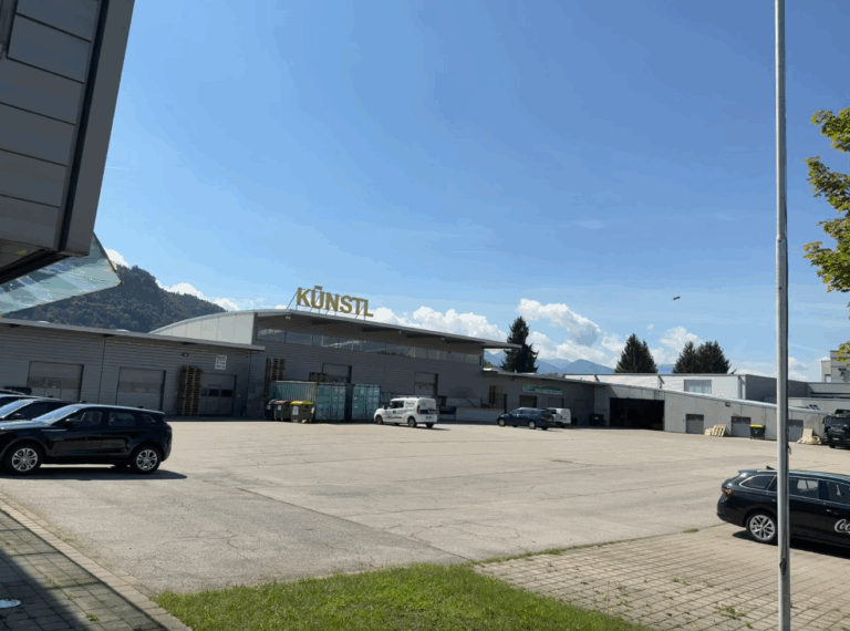 Kunst-L Einkaufszentrum, großes Parkdeck, Blick auf das moderne Bauwerk in Vorarlberg, Österreich, mit Bergen im Hintergrund, sonniger Tag, ideal für Freizeit und Einkaufen.